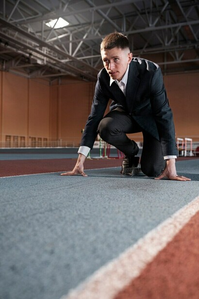A fit professional in a suit, gearing up for a run, embodies the perseverance and focus required to navigate the entrepreneurial struggle and rise to the top in the coaching industry