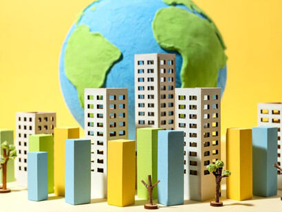 A globe made of paper displays small, intricately crafted paper buildings, symbolizing the world in a simple, artistic form