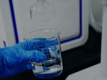 A lab technician wearing gloves is performing water filtration tests