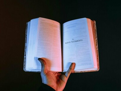 A hand holding out an open Bible, signifying a reminder to assess whether one’s actions align with scripture
