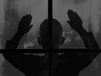 Um menino olha através de uma janela com as mãos levantadas, como que para impedir que o abanadonem
