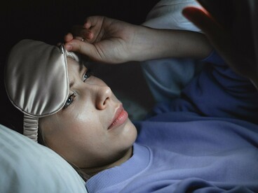 Deitada na cama e já preparada para dormir, a mulher ainda mantém os olhos voltados para o celular. O hábito de permanecer conectado até os últimos momentos do dia pode dificultar a transição entre a agitação das telas e o descanso