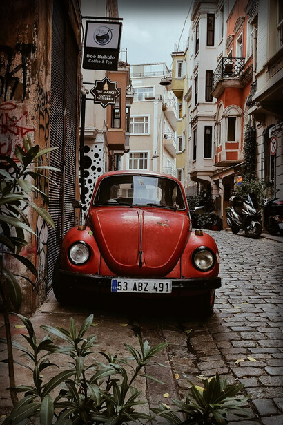 Volkswagen Maggiolino rosso classico parcheggiato in una strada stretta e acciottolata