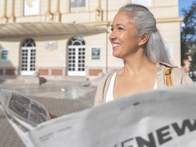 A woman reading a newspaper titled 'fake news,' symbolizing the post-truth era