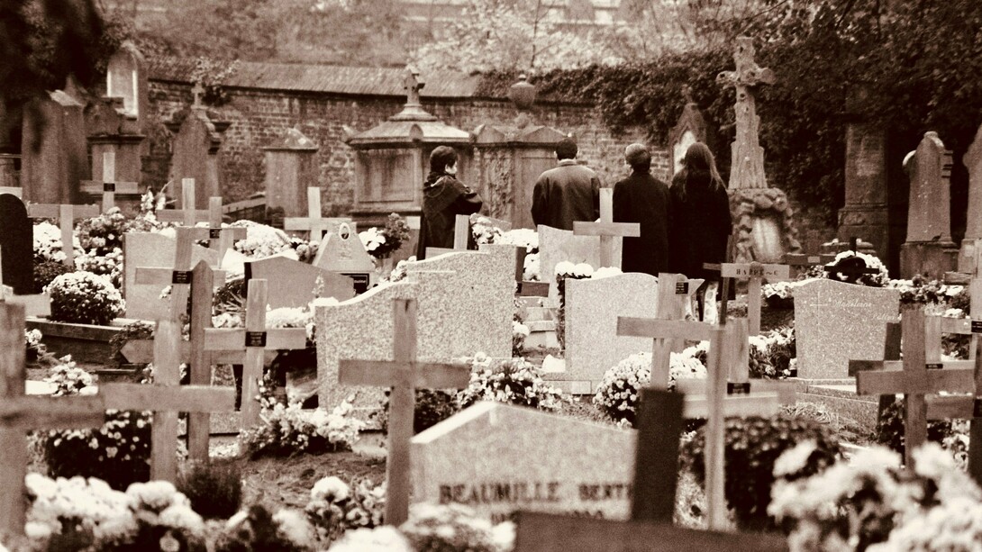 Grupo de pessoas presta homenagem a um ente querido em um cemitério. O enfrentamento da finitude envolve não apenas quem está partindo, mas também aqueles que permanecem e aprendem a conviver com a perda. A morte faz parte da experiência humana, e compreender esse processo pode ajudar a tornar o luto menos solitário