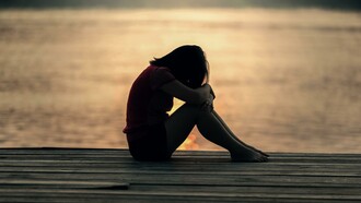 A person who is dealing with grief sitting by some water