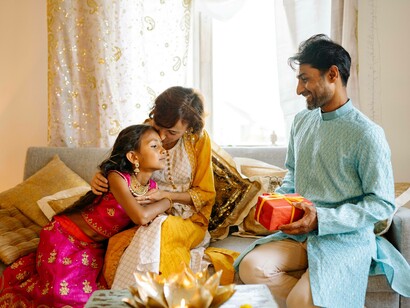 A young girl seeing that her father has a present is gravitating toward him