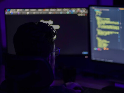 A man in a black long-sleeve shirt is working at a computer