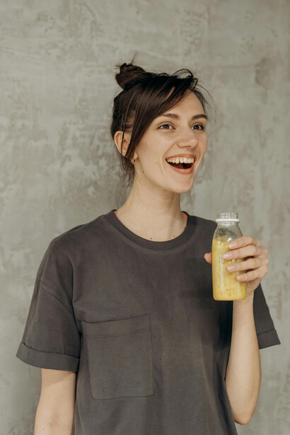 Woman holding a bottle of juice after a gym workout, representing a fitness influencer promoting healthy habits