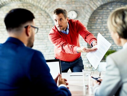 Un uomo d'affari infuriato sgrida i dipendenti durante una riunione