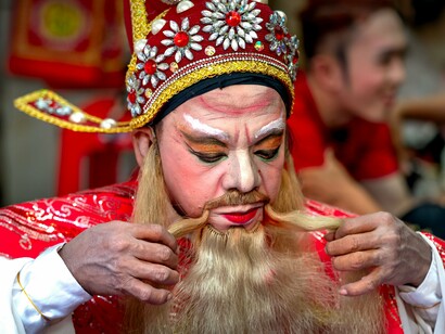 An opera actor making the final touches to his elaborate costume, reflecting the dreams Vương once held before hardship altered his path
