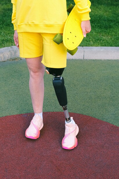 A person in yellow holding a skateboard 