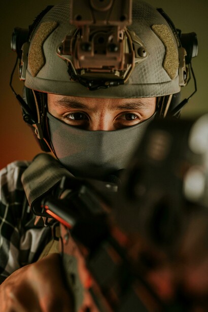 Camouflaged soldier in armored tactical gear, helmet on, aiming with precision
