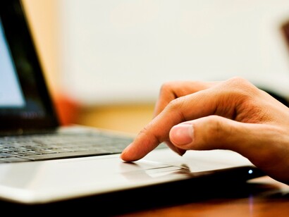 Una mano maneja un ordenador portátil