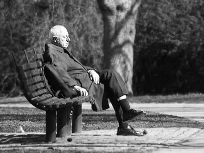 Un anciano sentado en el banco de un parque