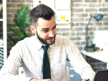 A man sits at a desk in front of a laptop, focused on his work