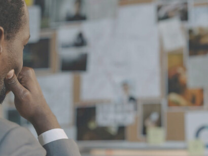 A thoughtful police officer, deeply engrossed in solving a cybercrime case, gazes intently at the investigative board