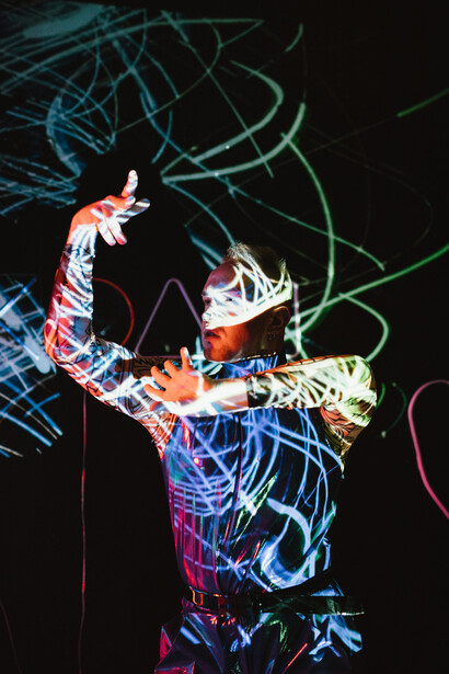 A man standing in a dark room illuminated by string lights, with lightning glowing inside his bod