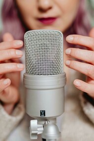 A woman placing her hand on a microphone