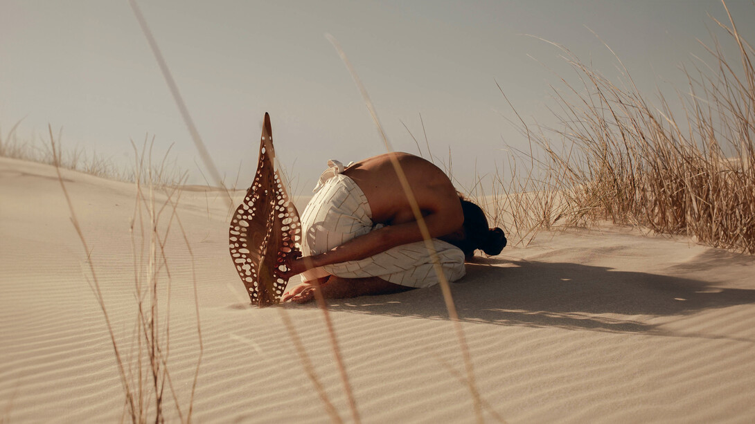A shared reverence, Karlien folding into the dunes beside ‘Diatom Bokeh’ from the Epiphanic series collaboration with Reticence Studio, photographed by Driaan Claassen