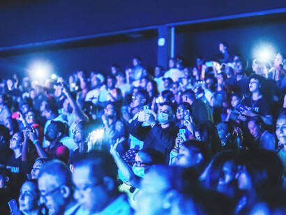 The audience is bathed in blue light inside the theatre