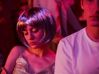 In a bustling nightclub, a Russian girl shines in a silvery dress and wig, capturing everyone's attention on the dance floor