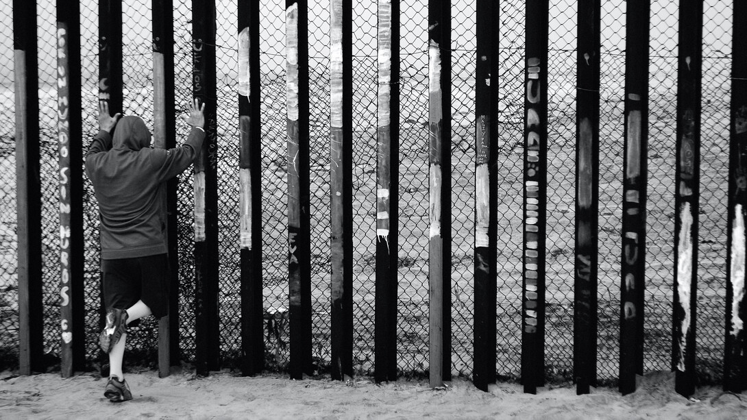 Migrante frente a las vallas que delimitan la frontera sur de los Estados Unidos