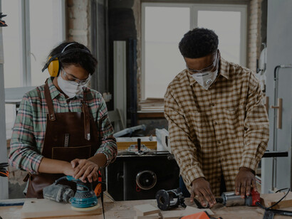 Man and woman working with a laptop inside a carpentry workshop, representing skilled professional teamwork and an innovative workplace culture