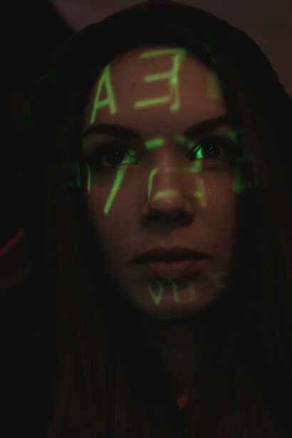A woman in a dark room with green text over her face