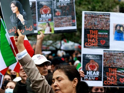 A woman holding up a picture of Mahsa Amini to remind them of the injustices committed in Iran