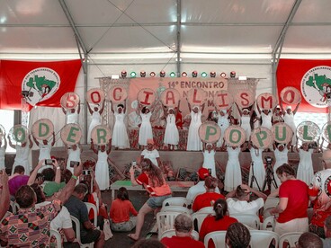Participantes de um evento do MST exibem cartazes formando as palavras "Socialismo" e "Poder Popular". A organização coletiva é apontada no artigo como um elemento central para a reconstrução das esquerdas