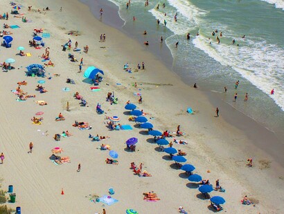 Umbrellas and towels stretch endlessly across the sand, a reminder of how quickly serenity turns into saturation