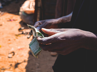 Des mains comptent des billets en circulation dans l’espace ouest-africain. Derrière les débats sur une éventuelle monnaie commune de l’AES, les réalités économiques imposent encore prudence, stabilité et coordination régionale