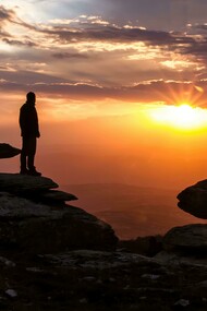 La sagoma di un uomo che si affaccia su un paesaggio al tramonto