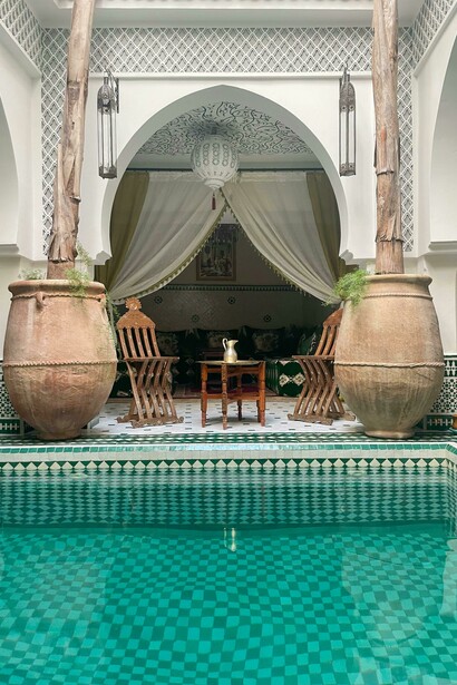 A white and blue tiled swimming pool set within the interior courtyard of a traditional riad in Marrakesh, Morocco