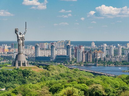 Motherland Monument among green trees on embankment in Kiev, Ukraine