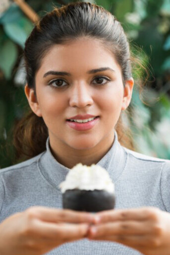 In a cozy café, a young Indian woman indulges in a creamy pastry—an everyday moment that mirrors India’s growing sugar intake