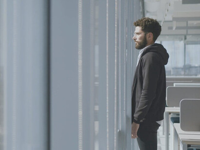 In a moment of silence, looking out from the office window, the weight of unspoken pain and unseen struggles becomes painfully clear on this man's face