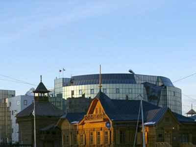 Edificio del banco ruso-asiático (finales del siglo XIX). A la izquierda las torres de las empalizadas (ostrog) restauradas de Yakutsk,  símbolo de la ciudad y edificio del tesoro del siglo XVIII. Al fondo la fachada de cristal del edificio Komdragmeta, Rusia 