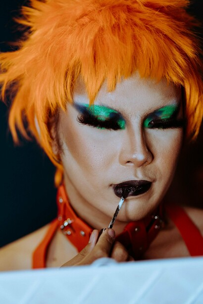 A captivating drag queen putting the finishing touches to their make-up,  highlighting the queer community’s commitment to pushing the boundaries of beauty and celebrating individuality through fearless creativity and style