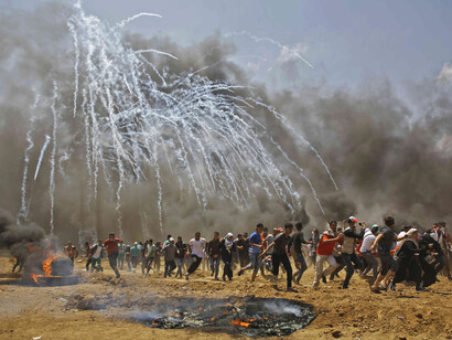 Personas palestinas huyendo de los gases lacrimógenos durante los enfrentamientos con las fuerzas de seguridad israelíes, tras la polémica de cambiar la embajada estadounidense a Jerusalén