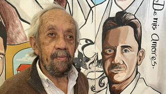 El artista Gastón González posa junto a un mural en que están representados los hombres insignes de San Felipe, Estado de México