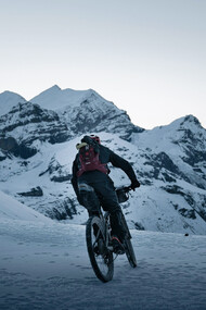 A cyclist riding through a snowy mountain trail, immersed in winter’s beauty, Nepal