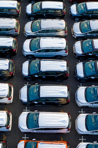 Drone shot of a massive car storage area where vehicles await distribution, illustrating worldwide car manufacturing