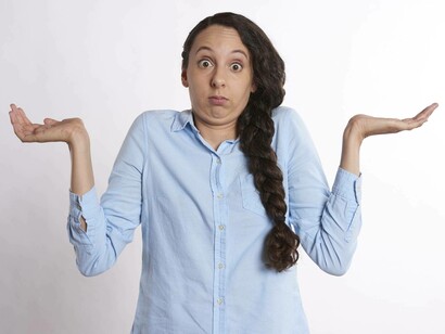 The woman in a blue shirt puts her hands up in confusion