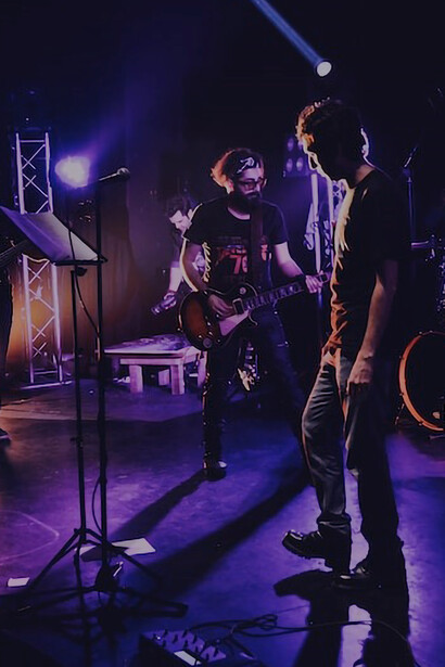 A guitarist in a black t-shirt rocking out on stage