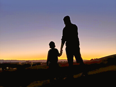 Un hijo va de la mano de su padre por el campo
