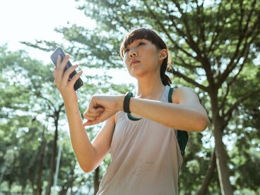A fitness enthusiast reviewing health data on her wearable device, representing the rise of connected technologies that track daily activities and wellbeing