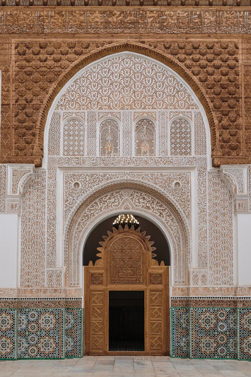 An arched ornate door in Marrakesh, Morocco, showing the intricate patterns and vibrant colors of Zellij