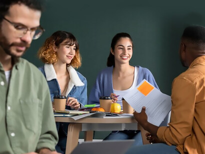 A young man presents his notes to fellow students during a collaborative study session in a diverse university classroom